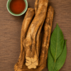 Dark herbal decoction liquid in a ceramic bowl surrounded by botanical leaves and wood bark specimens